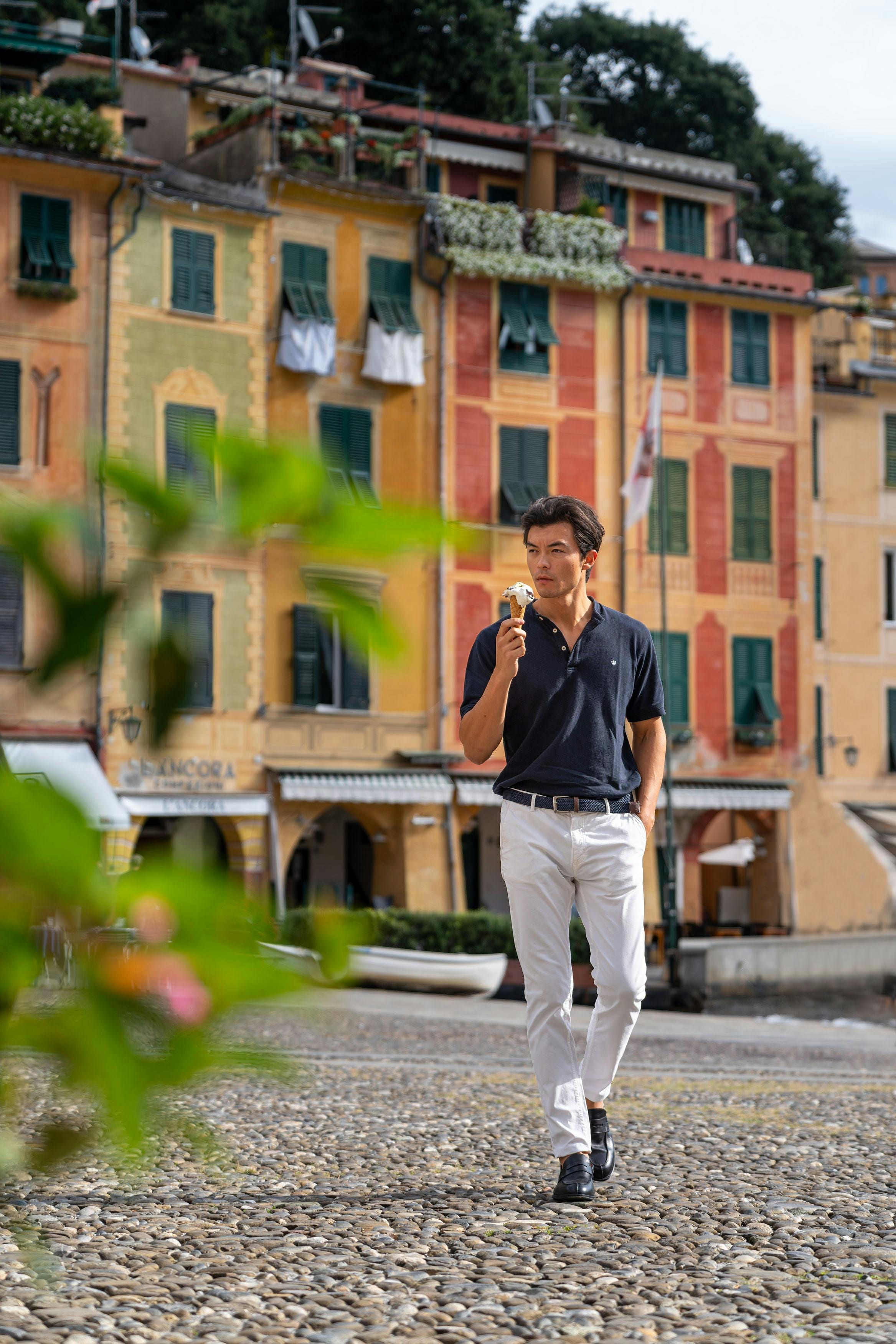 Man eating gelato in Portofino's piazzetta before pastel painted facades