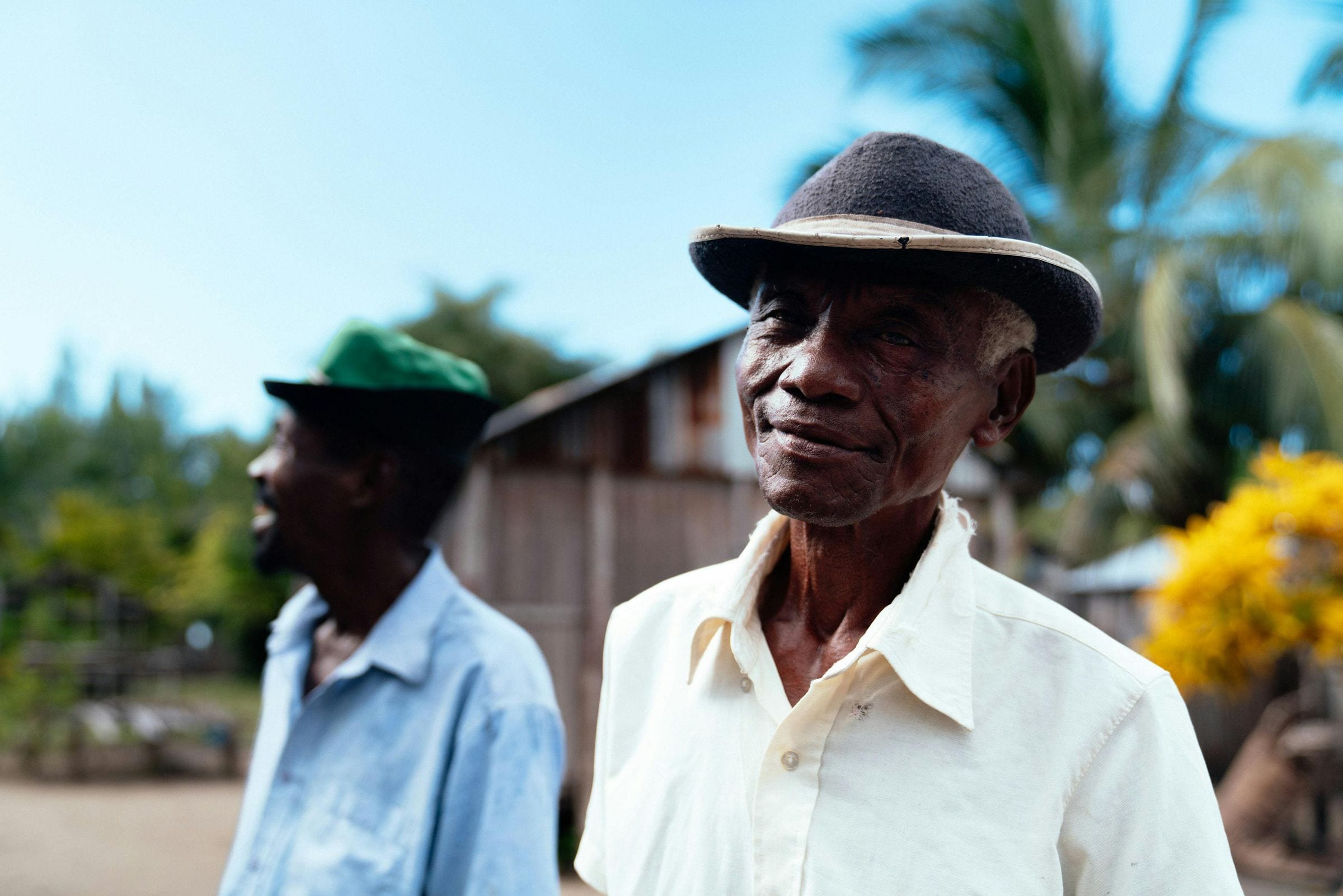 Portrait of an elderly man in a felt hat and white shirt, village behind