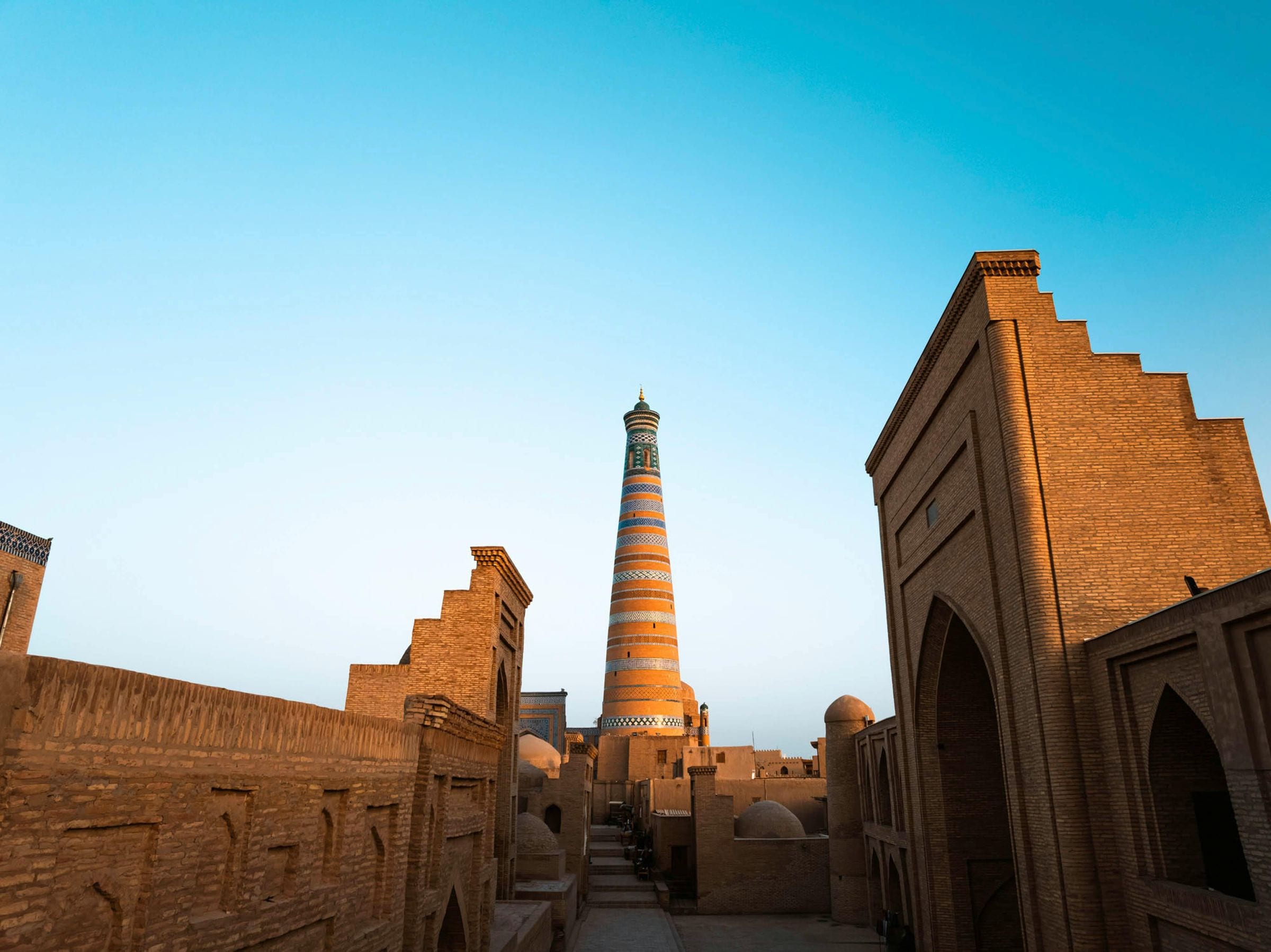 Striped Islam Khoja minaret rising above Khiva's brick old town at golden hour