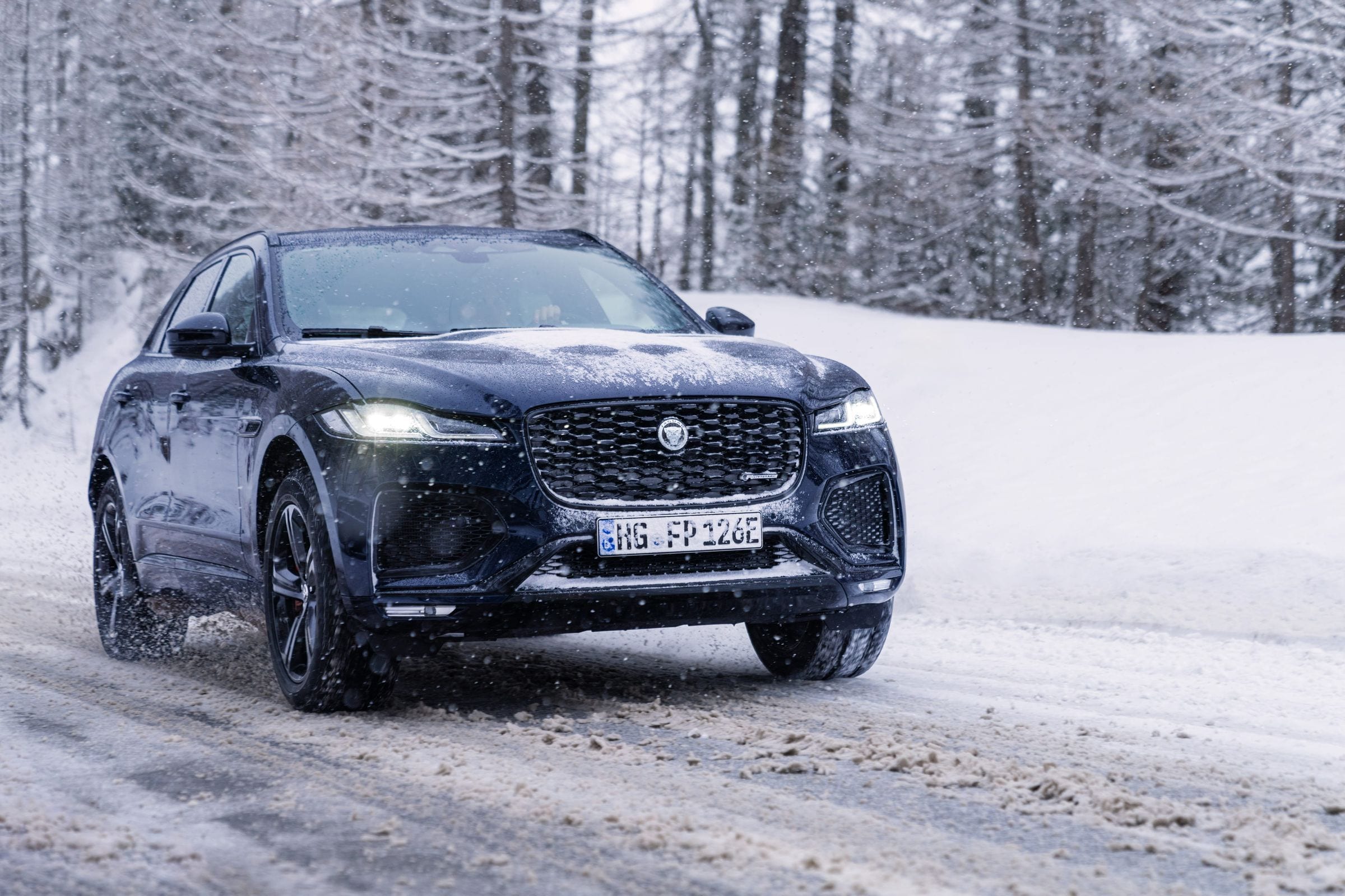 Inside the Jaguar F-PACE, a driver’s hands on the wheel with the navigation screen showing the Tirol route