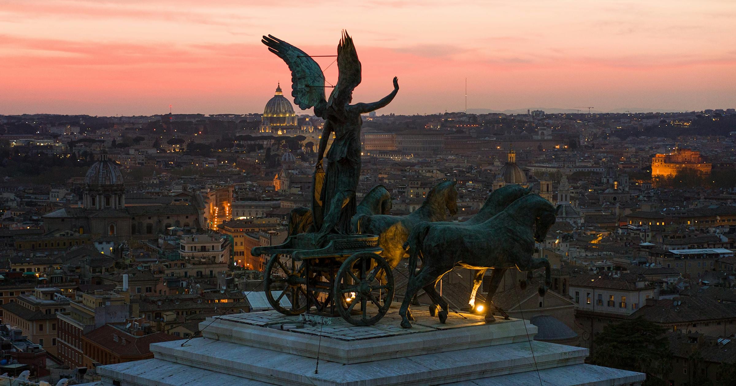 Bronze winged Victory quadriga atop the Vittoriano overlooking Rome at pink dusk