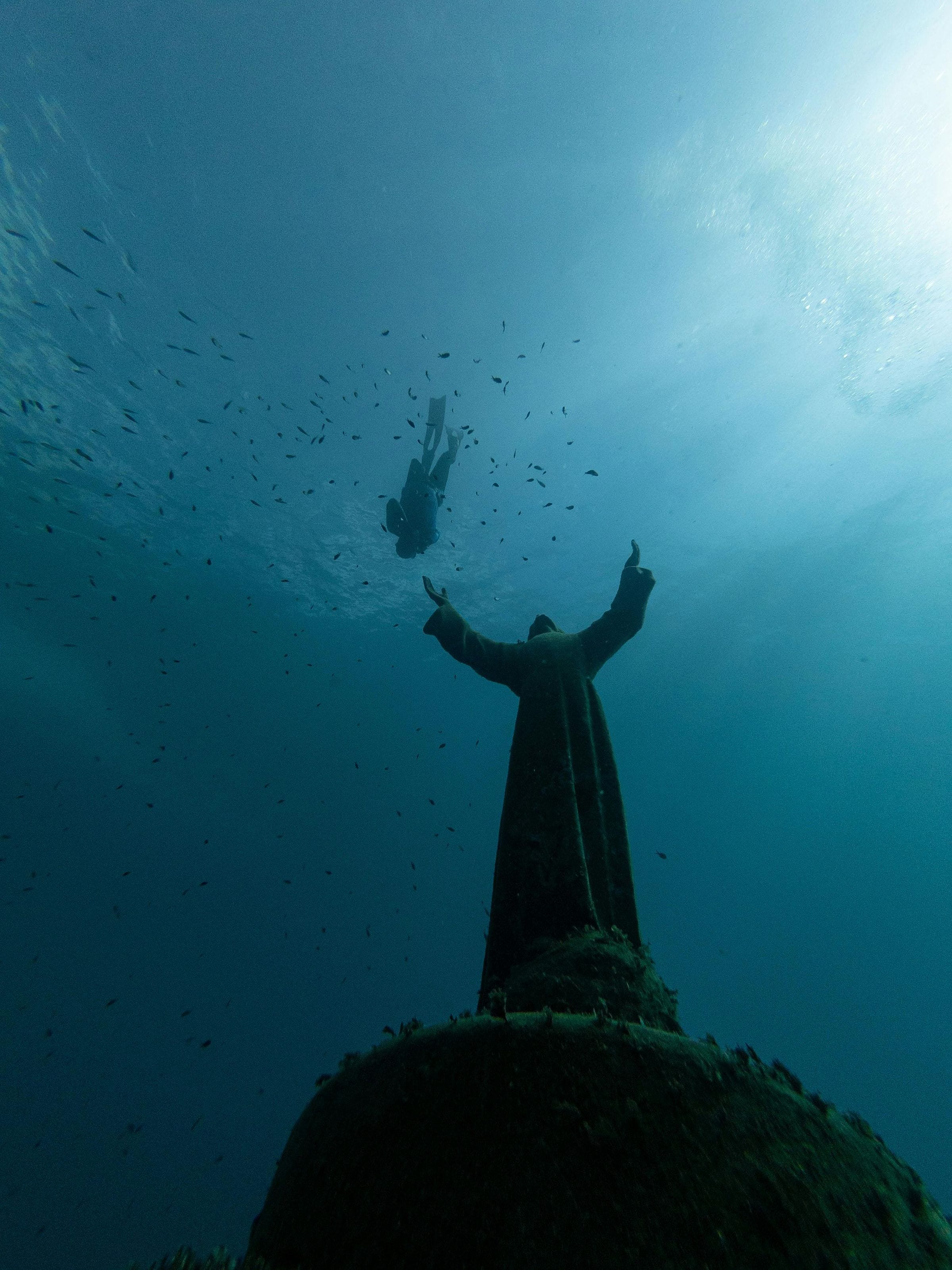 Freediver descending toward the submerged Christ of the Abyss statue off Portofino