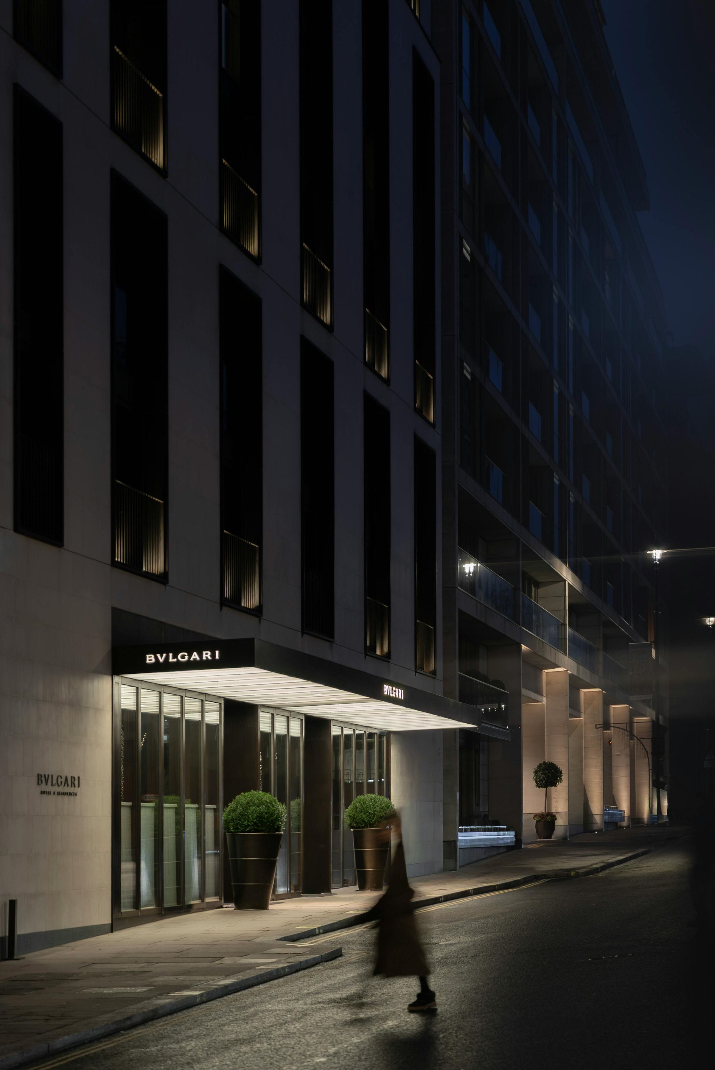Bvlgari Hotel London entrance glowing at night as a blurred figure passes on the quiet street