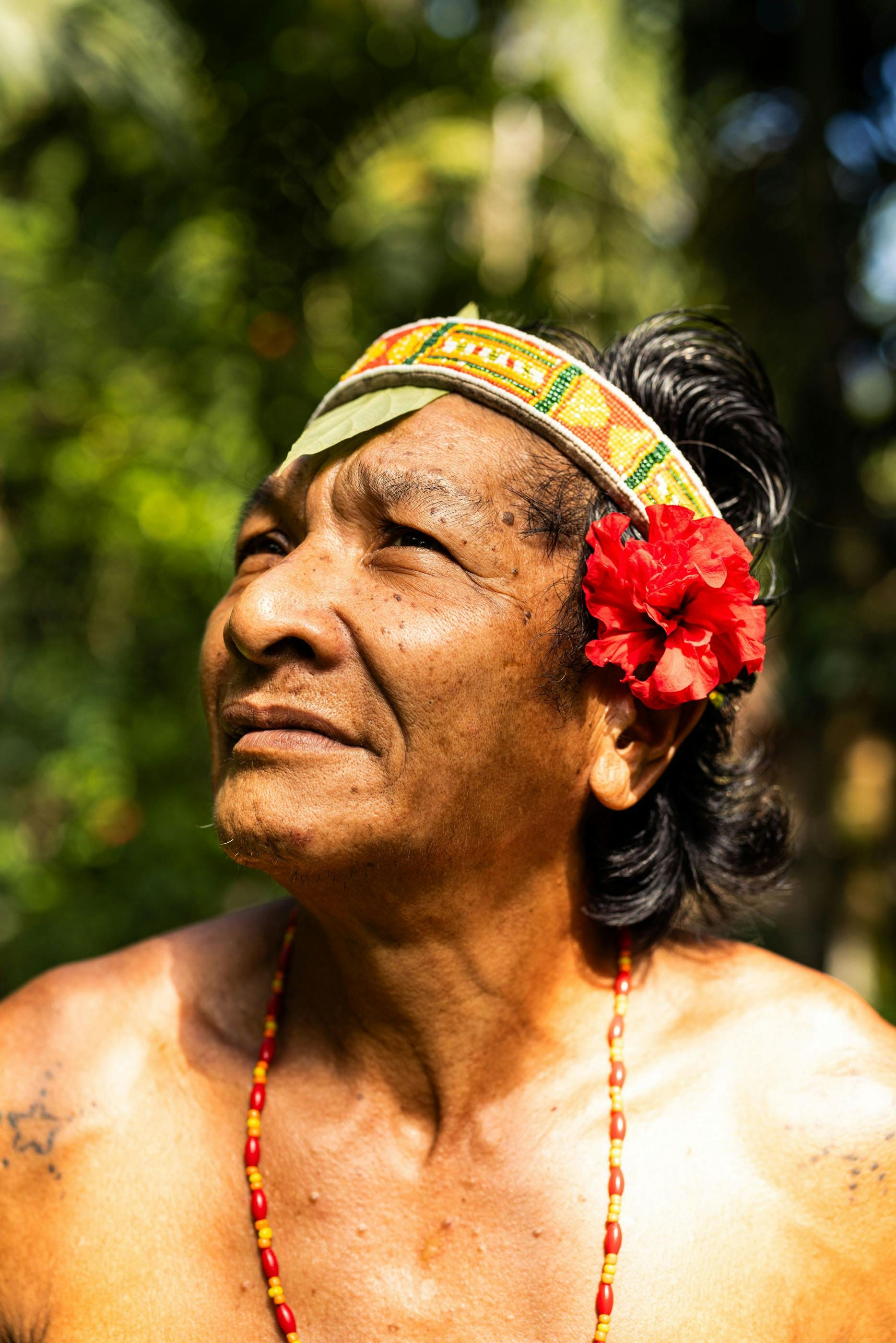 Mentawai elder gazing upward with a red hibiscus behind his ear