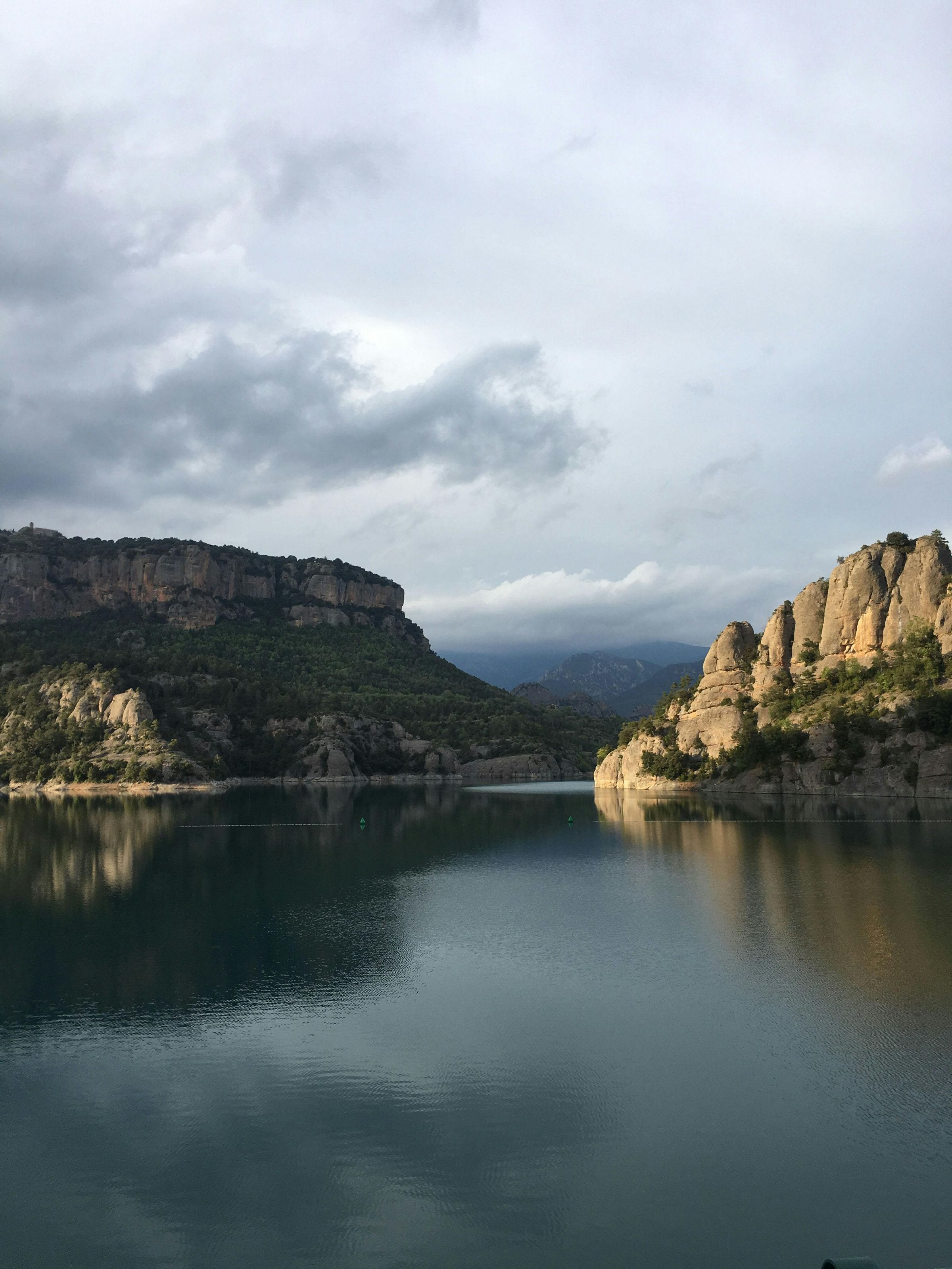 Calm reservoir between rocky cliffs under a moody, cloud-filled sky in inland Catalonia