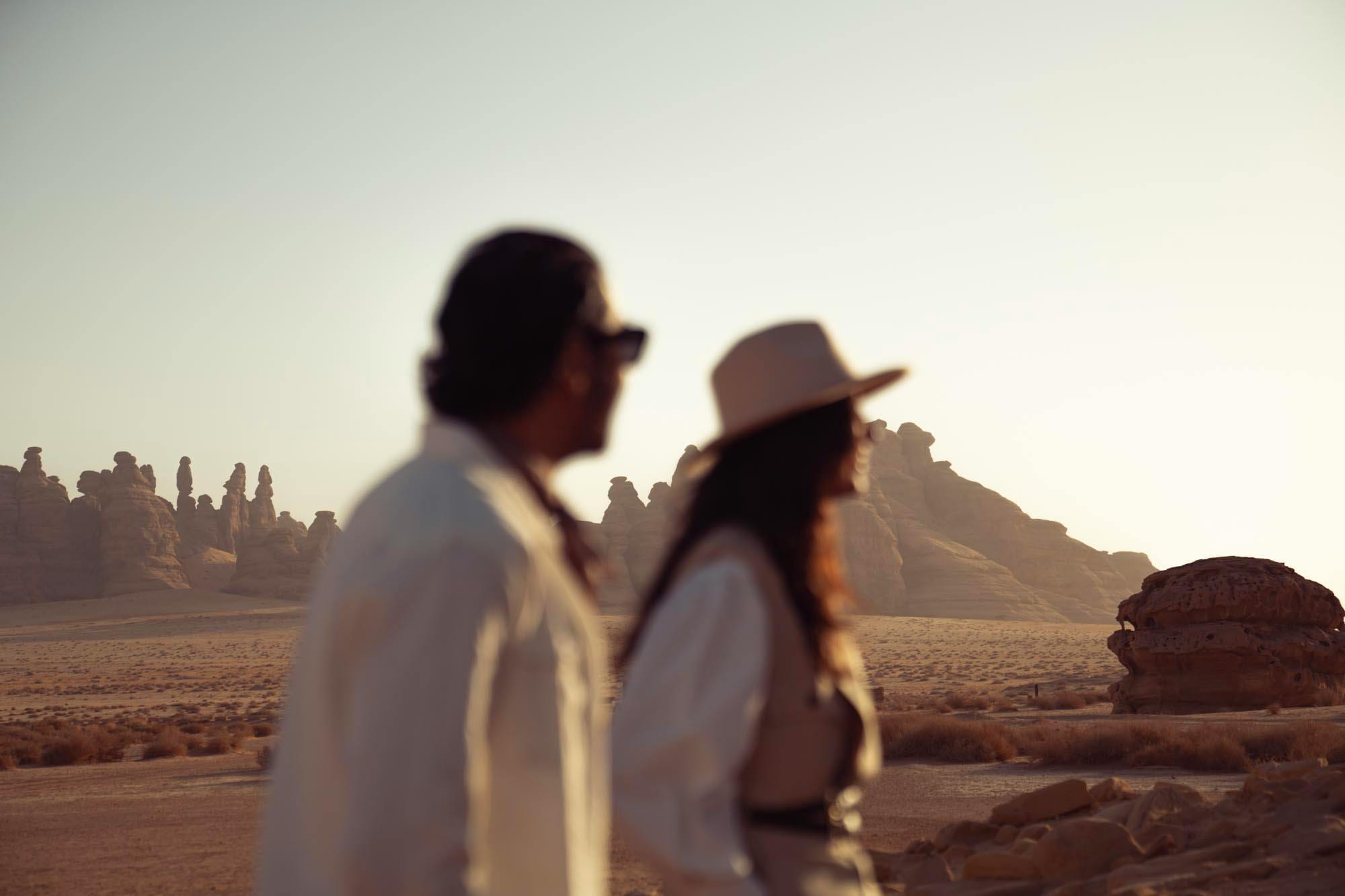 Couple in white overlooking desert sandstone spires at golden hour