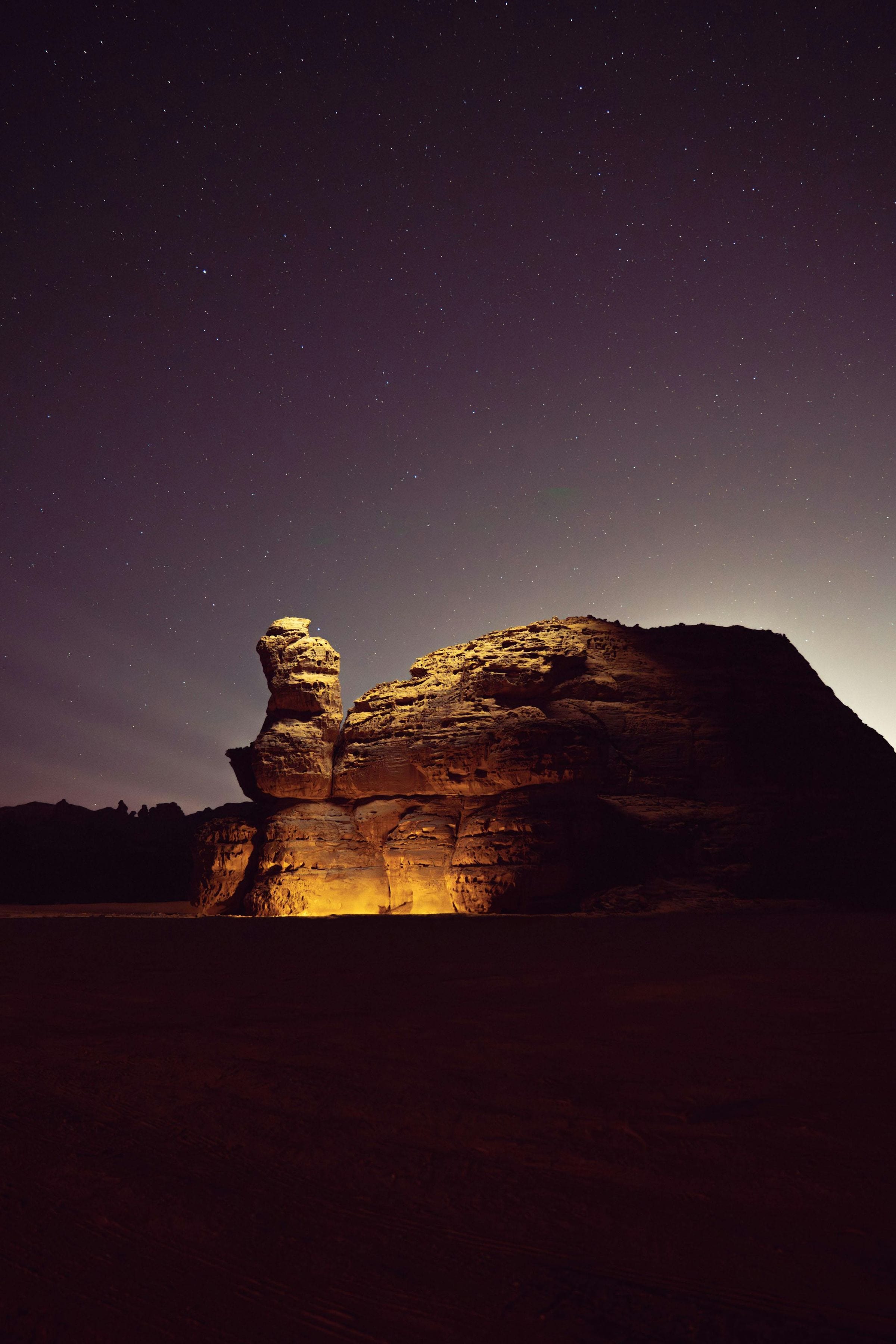Illuminated sandstone outcrop beneath a star-filled desert night sky