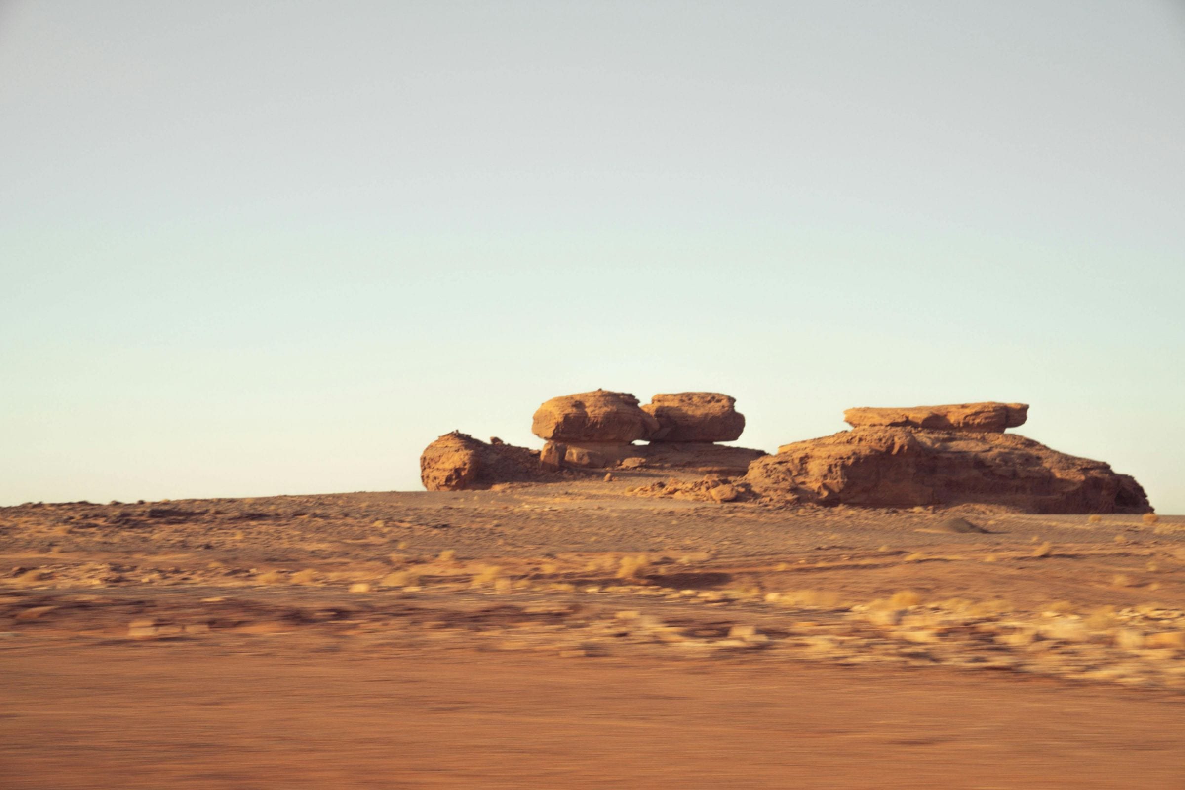 Mushroom-shaped desert rocks passing beyond a moving vehicle's window