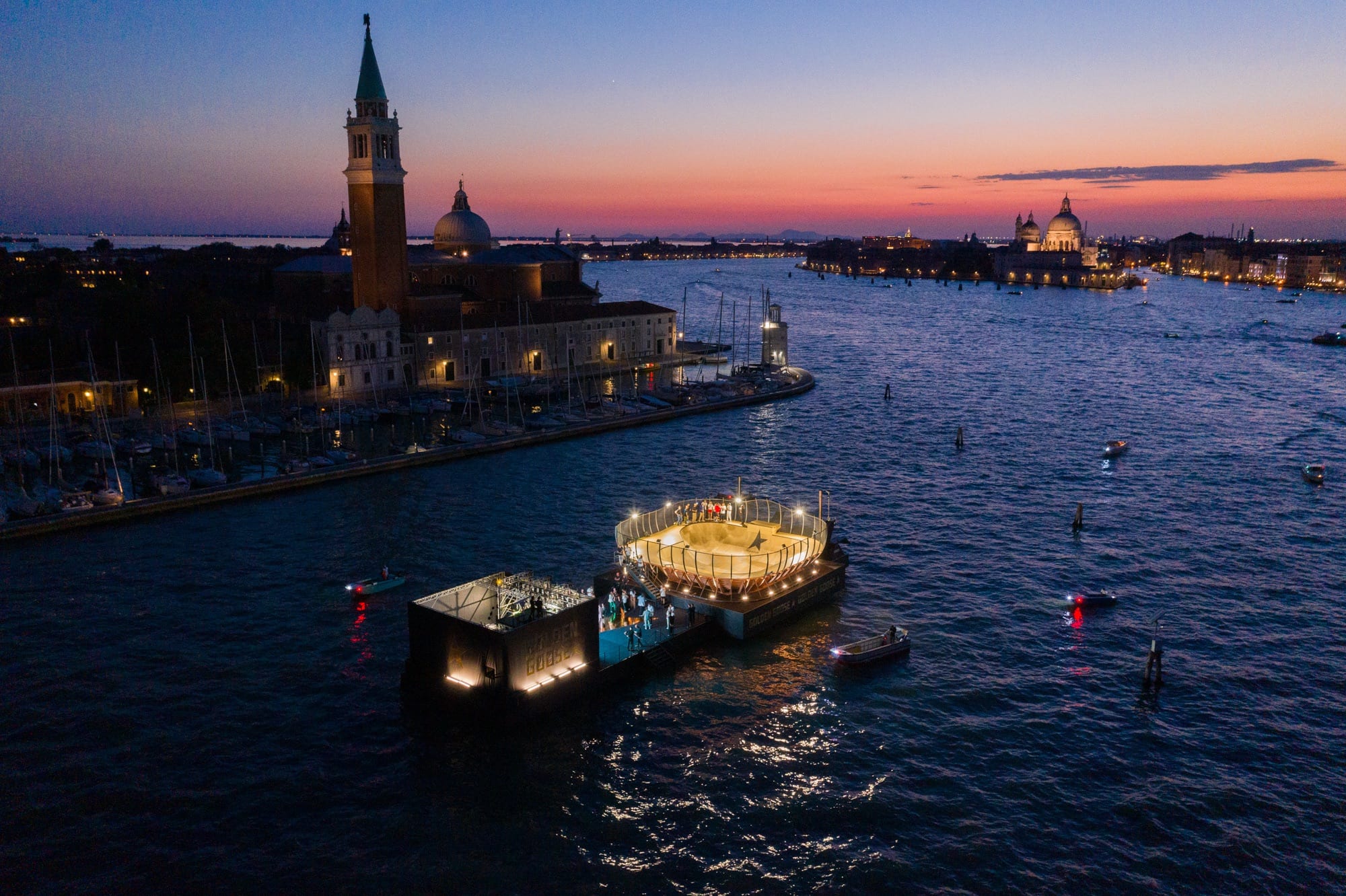 The lit floating skate bowl at sunset with the campanile of San Giorgio Maggiore across the Venetian Lagoon