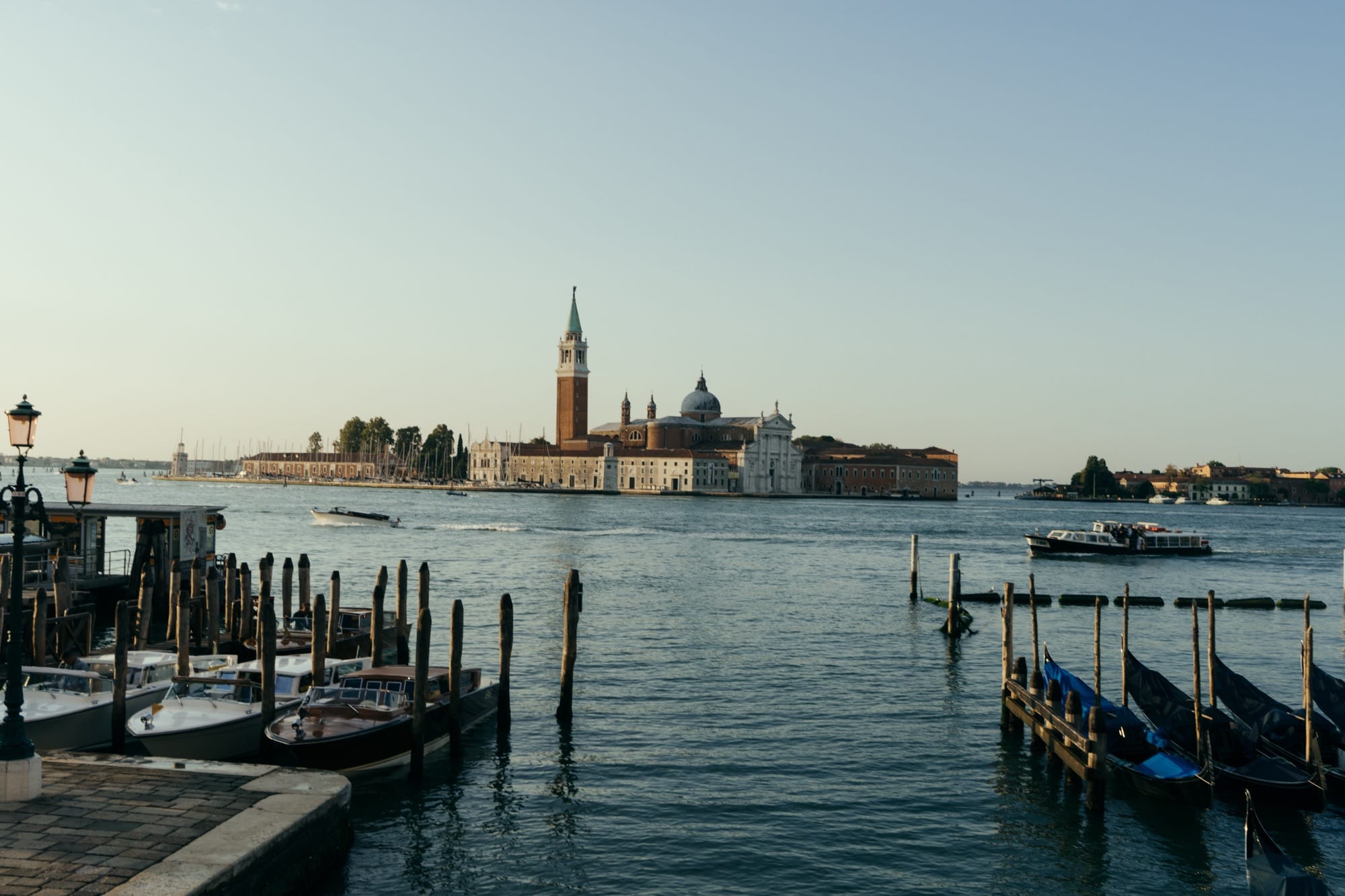 The island of San Giorgio Maggiore across the Venetian Lagoon at golden hour, moored boats in the foreground