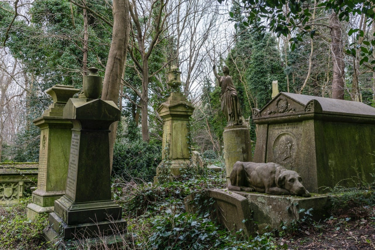 Ivy-clad Victorian tombs and a stone dog sculpture in Highgate Cemetery