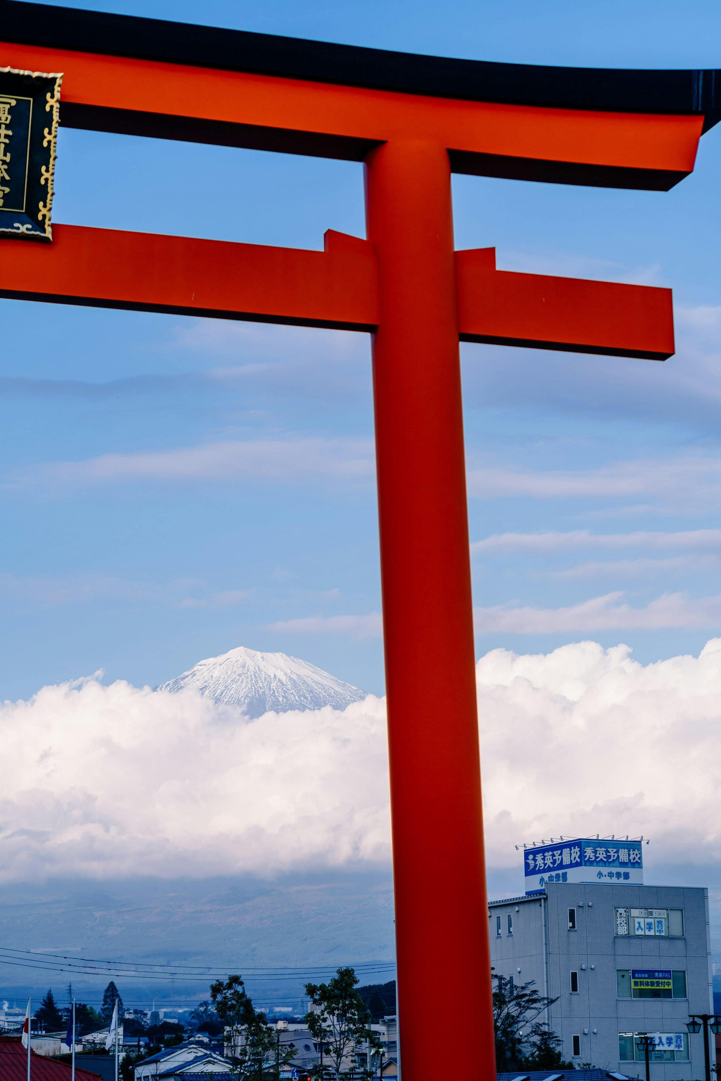 Snow-capped Mount Fuji framed by a bright red torii gate above the clouds