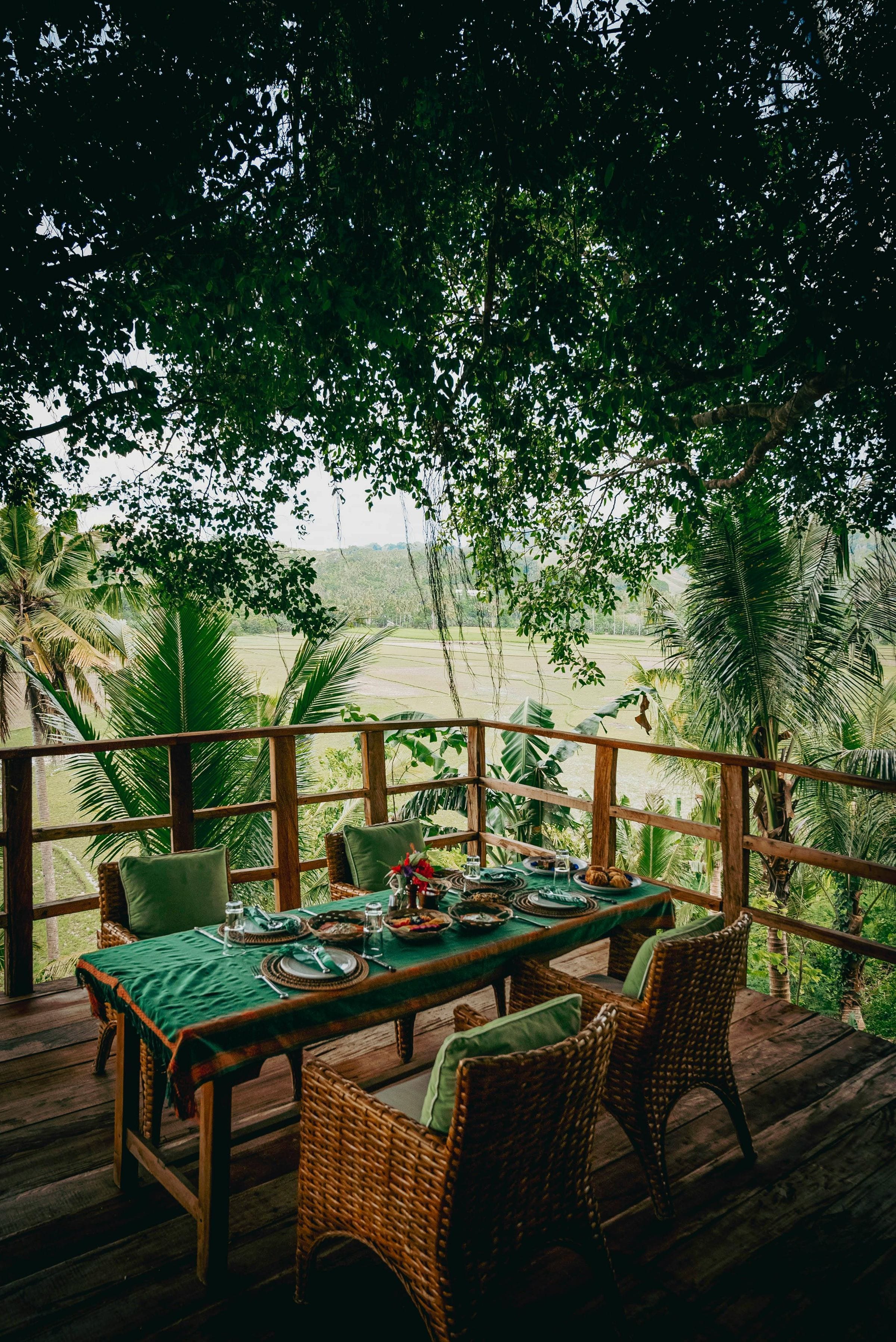 Breakfast table set on a shaded jungle deck overlooking Sumba's rice fields