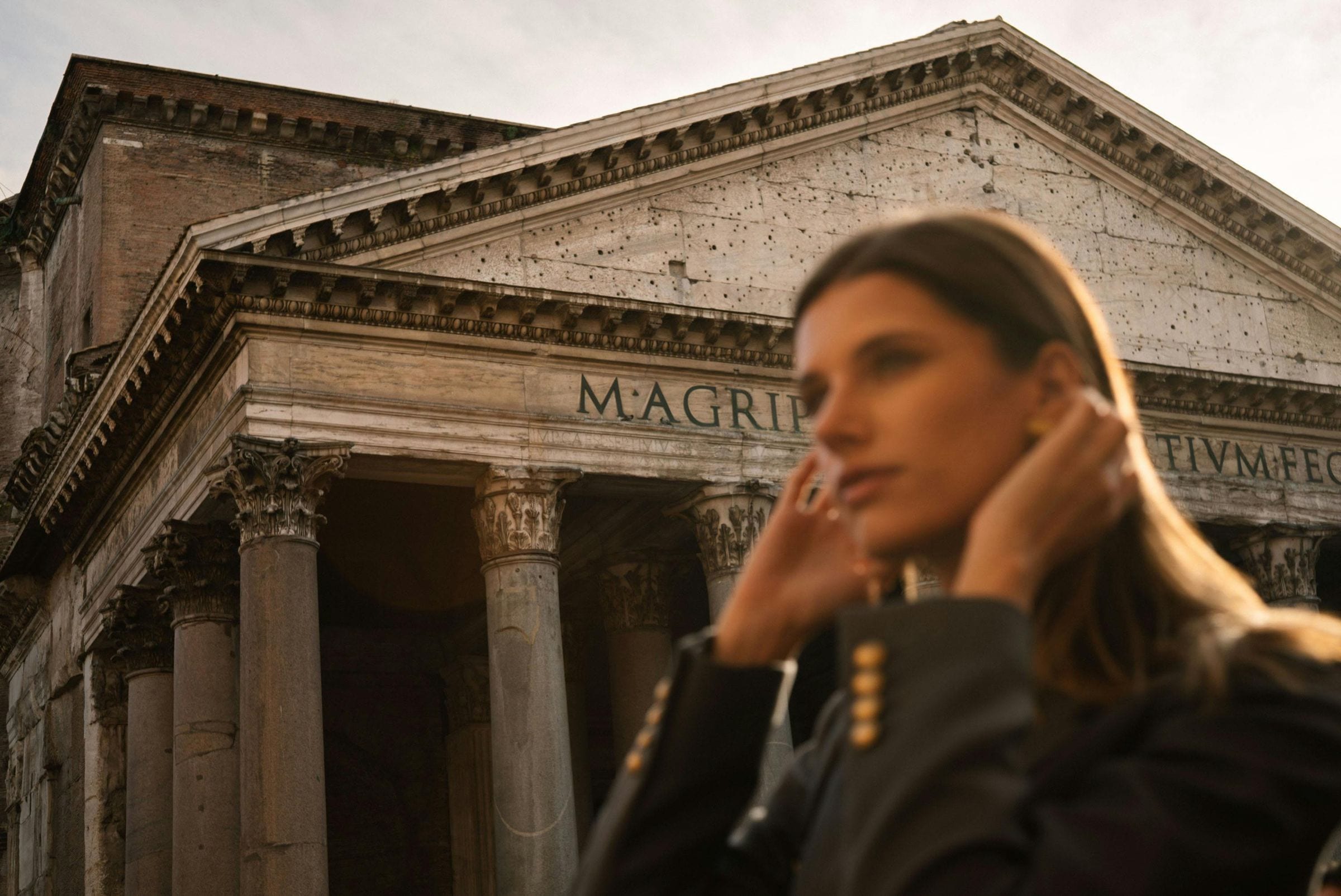 Woman adjusting her hair beneath the Pantheon portico inscription, Rome