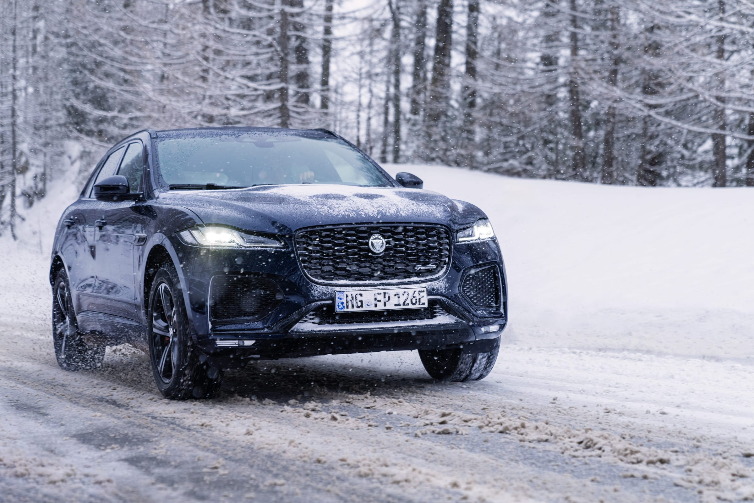 Inside the Jaguar F-PACE, a driver’s hands on the wheel with the navigation screen showing the Tirol route
